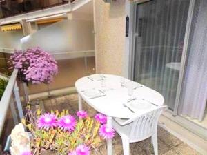 ヴォー・シュル・メールにあるAppartement de 2 chambres a Vaux sur Mer a 100 m de la plage avec terrasse amenagee et wifiの紫の花が咲くバルコニー(白いテーブル、椅子付)
