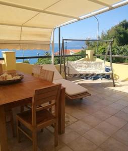 un patio con mesa, sillas y un columpio en 3 bedrooms villa at Magomadas 10 m away from the beach with sea view terrace and wifi, en Magomadas