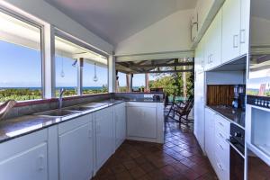 a kitchen with white cabinets and a view of the ocean at Villa avec piscine et vue sur la mer - Sainte Rose in Sainte-Rose