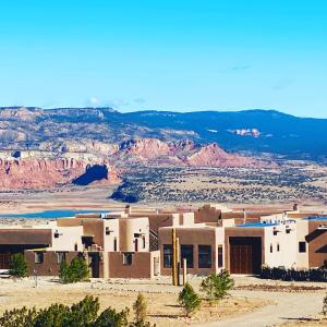 un edificio en el desierto con montañas en el fondo en The Grand Hacienda Inn with Breakfast, en Abiquiu