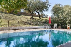 een zwembad met een rode parasol en een stoel bij 4 bedrooms villa with private pool enclosed garden and wifi at Valverde de Leganes in Valverde de Leganés