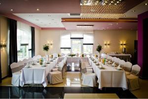 un salón de banquetes con mesas blancas y sillas blancas en Hotel Podkowa, en Płock