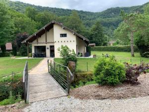 un pont en bois menant à un bâtiment avec une maison dans l'établissement Chalet l'Arcange 2 a 6 personnes au calme bord riviere Lison Franche Comte, à Nans-sous-Sainte-Anne