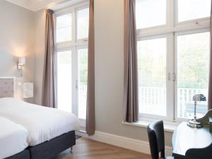 a bedroom with a bed and a desk and windows at Park Central Executive in The Hague