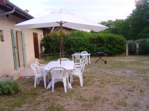 una mesa blanca y sillas con sombrilla en Charmante maison à Sarrazac avec piscine privée, en Sarrazac