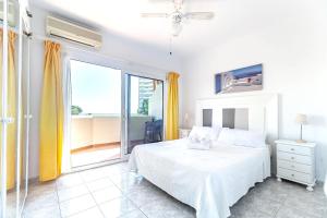 a white bedroom with a bed and a large window at Sea View Apartment in Benalmádena, Shared Pool in Benalmádena +13 photos