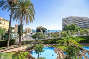 a resort with a swimming pool and palm trees at Sea View Apartment in Benalmádena, Shared Pool in Benalmádena