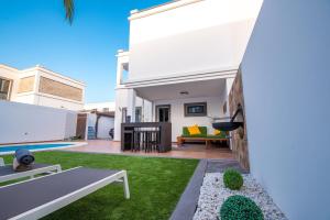 ein weißes Haus mit einem Hinterhof und einem Surfbrett in der Unterkunft Elegant Villa Playa Blanca with Pool in Playa Blanca