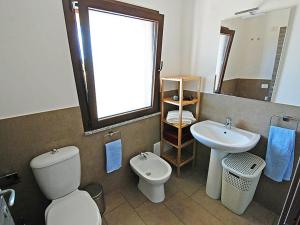 a bathroom with a toilet and a sink and a mirror at 2 bedrooms house with enclosed garden and wifi at Is Potettus in SantʼAnna Arresi