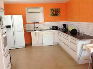 eine Küche mit weißen Geräten und einer orangefarbenen Wand in der Unterkunft Villa de 4 chambres avec piscine privee jacuzzi et jardin clos a Saint Privat des Vieux in Saint-Privat-des-Vieux