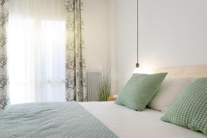um quarto com uma cama com almofadas verdes e uma janela em Aosta Centre Apartments - Battaglione 10 em Aosta