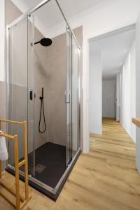 um chuveiro de vidro num quarto com piso de madeira em Aosta Centre Apartments - Battaglione 10 em Aosta