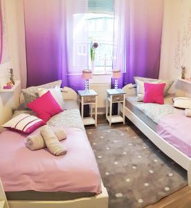 2 łóżka w pokoju z fioletowymi ścianami i różowymi poduszkami w obiekcie ELENA flat Lavendel Duisburg Zentrum w mieście Duisburg