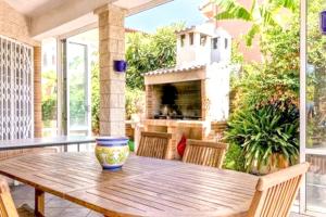 una mesa de madera y sillas en un patio con chimenea en 3 bedrooms villa with private pool enclosed garden and wifi at Marratxi 9 km away from the beach, en Palma de Mallorca