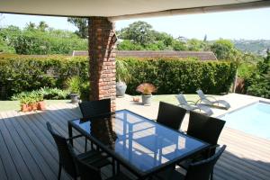 Un patio con mesa y sillas y una piscina. en Summit Place, en East London