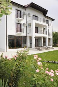 a large white building with windows and pink flowers at Pensiunea Velvet in Iaşi