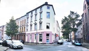 un bâtiment rose et blanc dans une rue de la ville dans l'établissement ELENA flat Tulpe Duisburg Zentrum, à Duisbourg