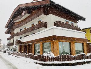 dom pokryty śniegiem z płotem w obiekcie Hotel Ciampian w mieście Moena