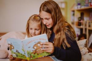 Eine Frau, die einem kleinen Mädchen ein Buch vorliest in der Unterkunft Haus Sonnblick in Abtenau