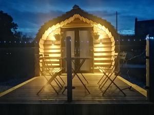 a wooden gazebo with two chairs and a table at Glamping Pod for 2 Pod Beag Na Haun Eriskay in Eriskay