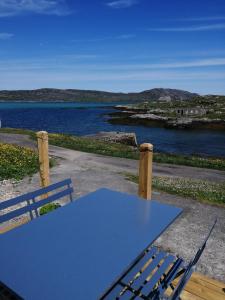 a blue table and chair on a patio with a view of the water at Glamping Pod for 2 Pod Beag Na Haun Eriskay in Eriskay