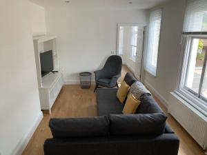 een woonkamer met een zwarte bank en een televisie bij One Bedroom flat in Whitstable with free parking in Whitstable