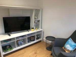 una sala de estar con TV en un centro de entretenimiento blanco en One Bedroom flat in Whitstable with free parking, en Whitstable