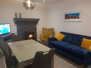 sala de estar con sofá azul, mesa y chimenea en Jack's Place Beautiful 3-Bed House Donegal, en Stranorlar