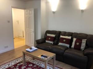 a living room with a leather couch and a coffee table at Oaklawn serviced apartments in Woking