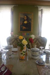 - une table à manger avec des vases et un portrait d'une femme dans l'établissement Villa Felice, à Giardini Naxos