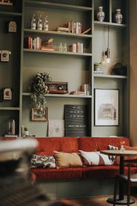 een rode bank in een woonkamer met boekenplanken bij FINCH Boutique Hotel, downtown in Deventer