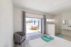 a bedroom with a bed and a chair and a balcony at 189 Casa Del Playa in Yzerfontein