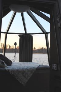 uma cama num quarto com uma grande janela em AuroraHut Aurantola em Kouvola