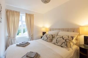 1 dormitorio con 1 cama con sábanas blancas y ventana en Cozy Nook a cosy 2-Bed House in Oakham Rutland en Oakham