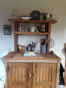 a wooden cabinet with wooden doors in a room at Cosy woodland off grid Shepherds Hut - Hazel in Castle Douglas