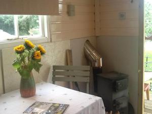 wazon z żółtych kwiatów siedzący na stole w obiekcie Cosy Shepherds Hut nr Kynance cove w mieście Lizard