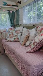 sypialnia z łóżkiem z różową kołdrą i poduszkami w obiekcie KItty unique 60s caravan set in pretty garden w mieście Lizard