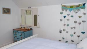 a bedroom with a bed and a mirror and a dresser at Wellspring Cottage nr Kynance Cove in Lizard