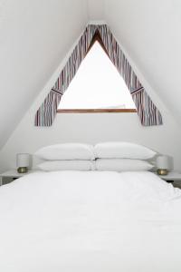 a bedroom with a bed with a triangular window at Seaside Chalet - Sleeps 6 in Kingsdown