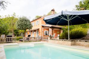 een groot zwembad met een parasol voor een huis bij Home set in olive grove with stunning views in Mondavio