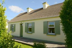 a white house with green shutters on it at 4-Bed Cottage in Co Galway 5 minutes from Beach in Inverin