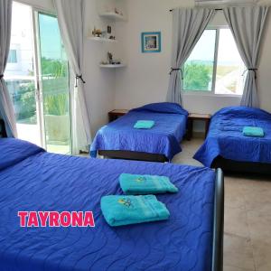 trzy łóżka w pokoju z niebieską pościelą w obiekcie Casa de Mony w mieście Santa Marta