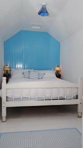 a white bed with a blue headboard in a room at Cosy & Quirky Cottage nr Kynance cove in Lizard