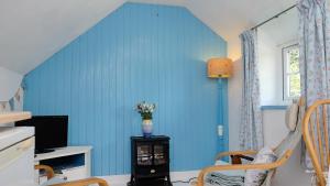 a room with a blue wall with a vase of flowers at Cosy & Quirky Cottage nr Kynance cove in Lizard
