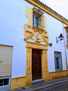 un edificio blanco y amarillo con puerta marrón en Rincón de la Fuenseca, en Córdoba