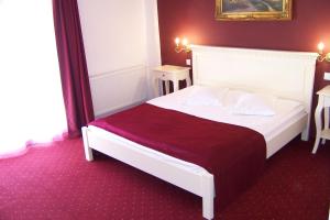 sypialnia z białym łóżkiem i czerwonym kocem w obiekcie Pensiunea Velvet w Jassach