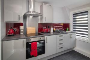 una cocina con armarios blancos y toallas rojas en New Luxury Seaview Apt3 Free Parking Special Deal, en Blackpool