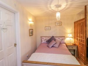 a bedroom with a bed with purple pillows on it at Amelyah Studio Cottage in Beautiful Countryside in Winscombe