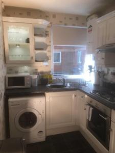 a kitchen with a washing machine and a microwave at Cosy 2-Bed Apartment near the beach in Morecambe in Morecambe