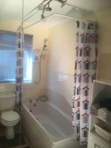 a bathroom with a tub and a toilet and a shower curtain at Cosy 2-Bed Apartment near the beach in Morecambe in Morecambe